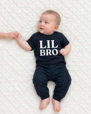 Baby on a white quilt with stacked LIL BRO lettering