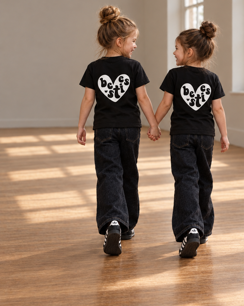 Girls holding hands with matching white Besties hearts on burgundy and black shirts