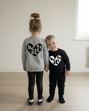 Little boy holding his sister’s hand and leaning into her