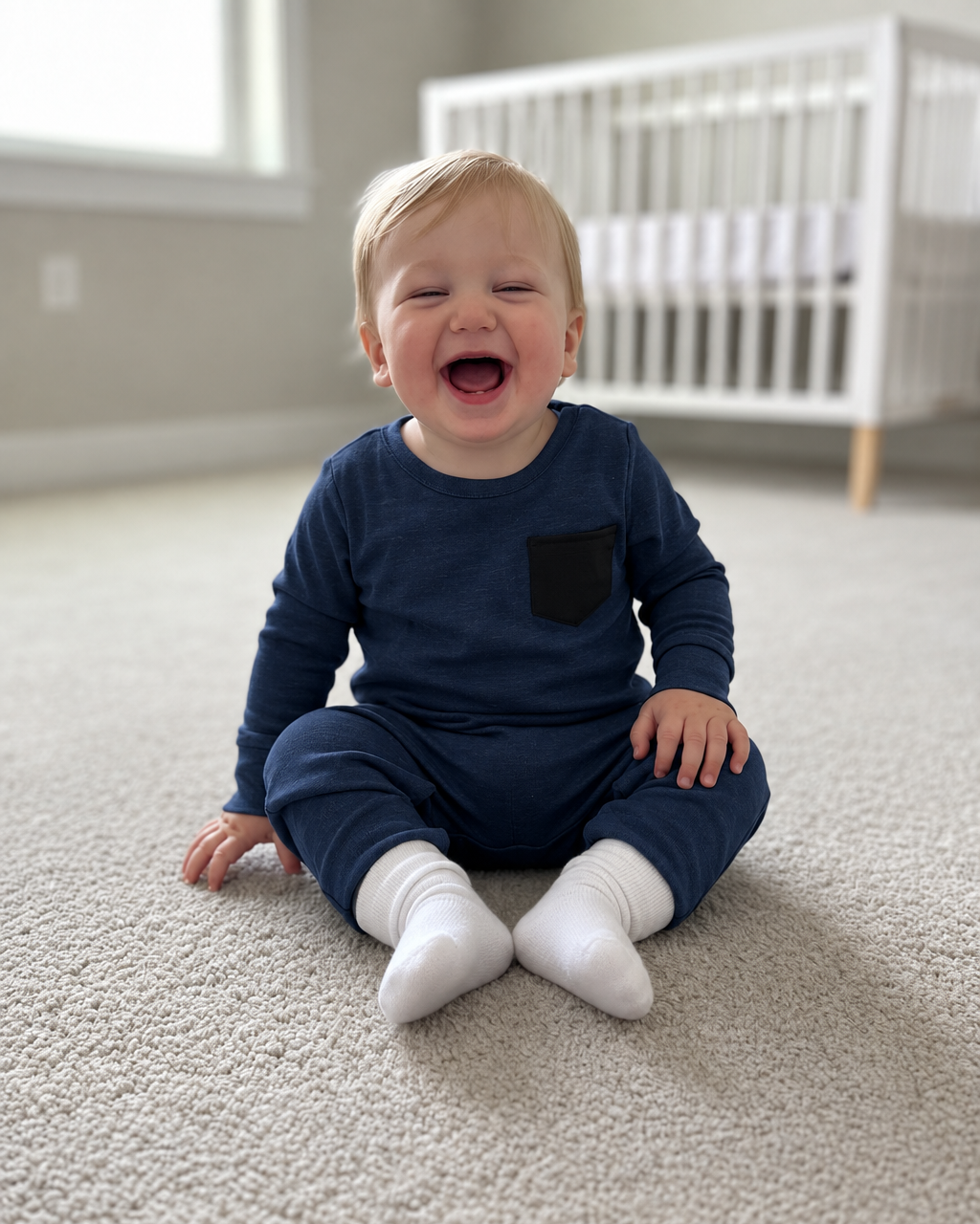 Little boy in a navy romper with a black chest pocket