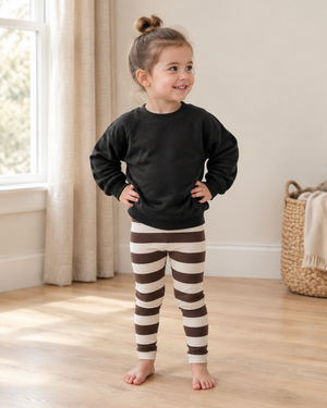 Little girl in brown-striped leggings and a slouchy black sweater