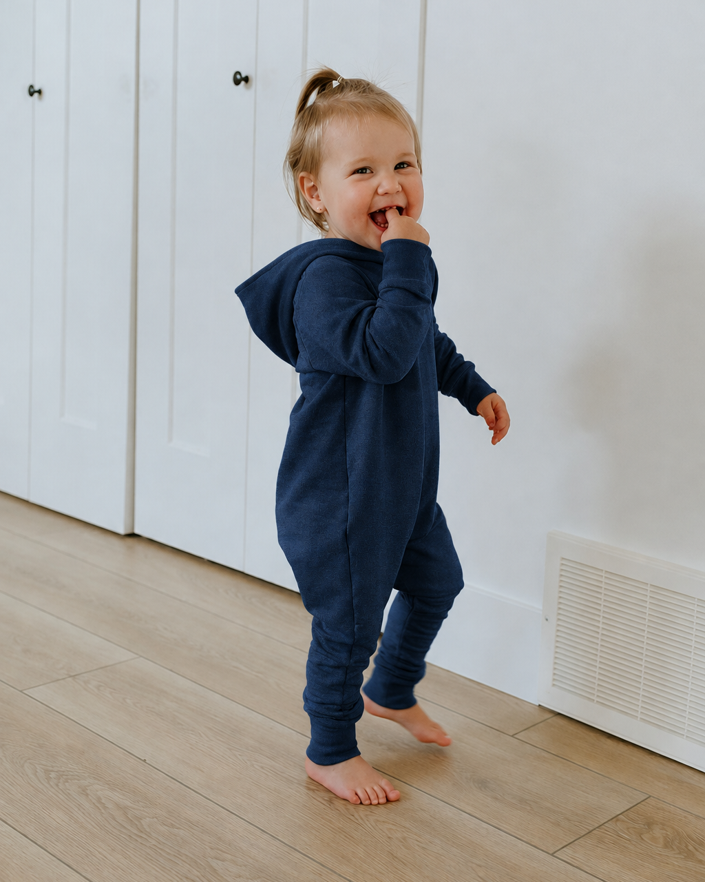 Little girl wearing a navy hooded romper