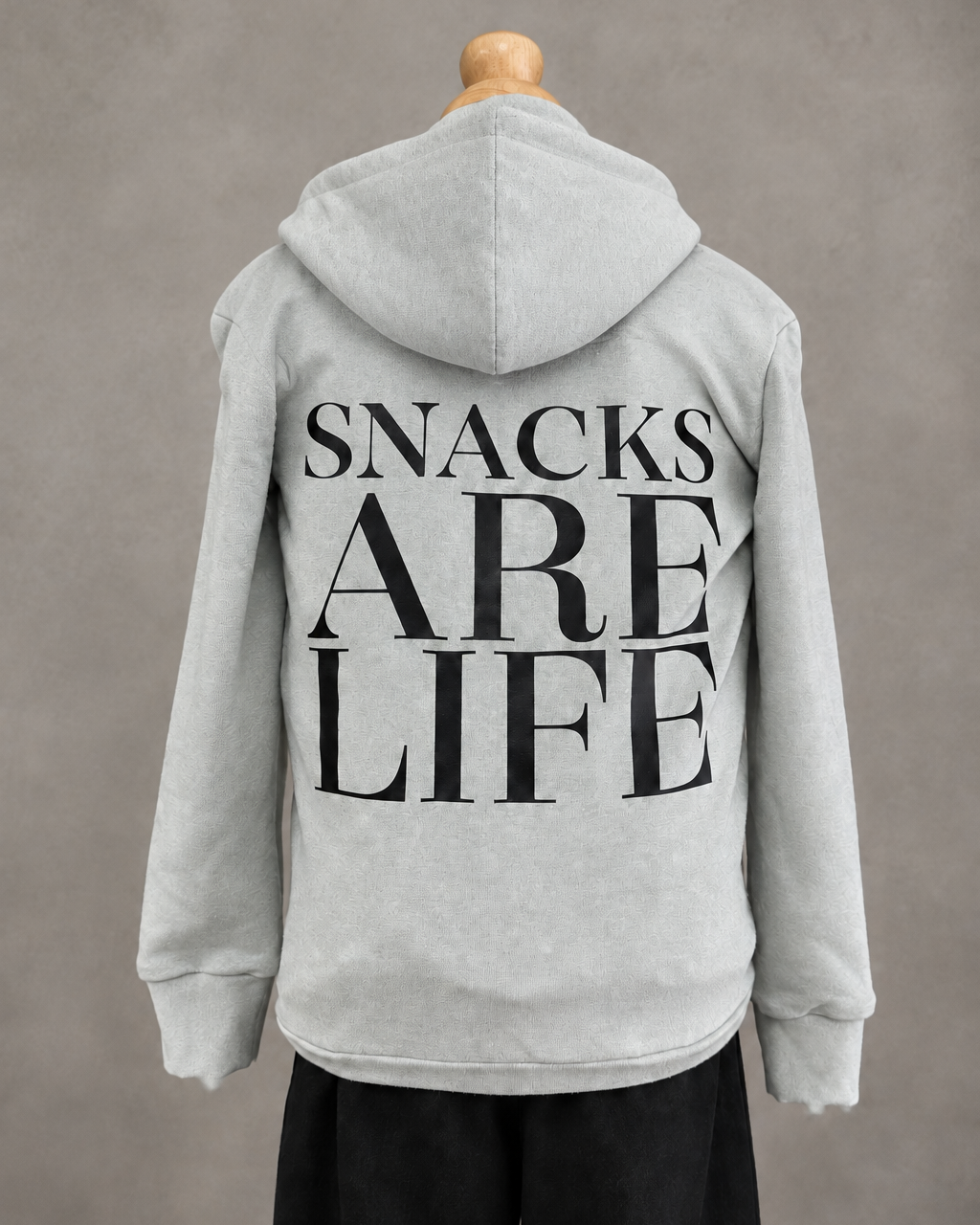 Girl having a snack at a moody kitchen island wearing a Snacks Are Life hoodie and burgundy pants