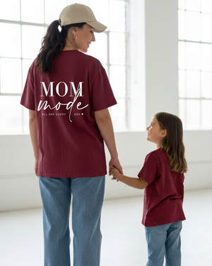 Mother in a burgundy shirt with a white MOM mode decal and daughter in a burgundy shirt with small randomly oriented bow prints