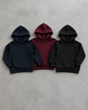 Navy, burgundy and black hoodies on a light concrete background