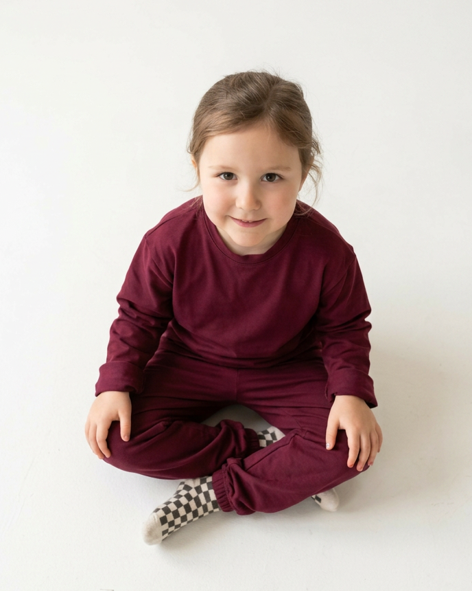 Boy seated on a stool wearing a matching navy shirt and pants