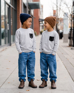 Two boys in relaxed pocket sweaters on a modern street in fall