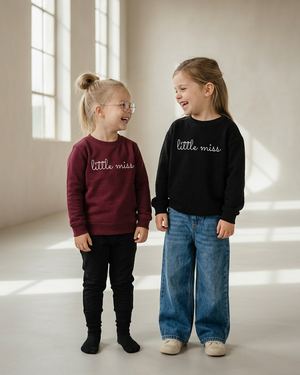 Two girls laughing together in burgundy and black little miss sweaters