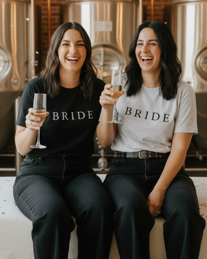 Two women in black and heather-grey BRIDE tees